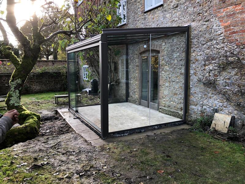 Glass veranda with aluminium frame installed on a traditional grade II listed stone house in Hampshire