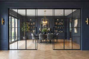 Crittall style internal sliding glass door dividing a large living room and dinning area.